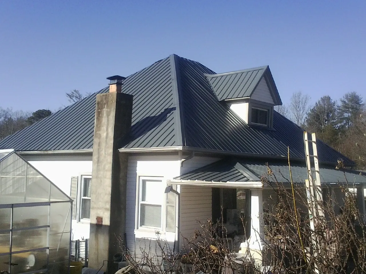 Dark blue standing seam metal roof on a white farmhouse with dormer — Slate & Tile Roof Repair by Roofing Brothers in Dana