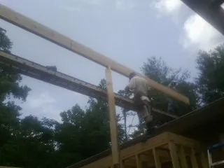 Carpenter setting a ridge beam over a new addition frame — Ice Dam Removal by Roofing Brothers in Dana