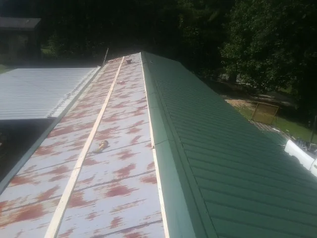 Old rusted panels beside newly installed green metal roofing — Wind Damage Roof Repair by Roofing Brothers in Dana